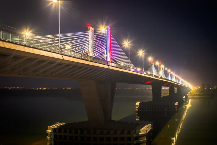 An illuminated cable-stayed bridge above dark water at night