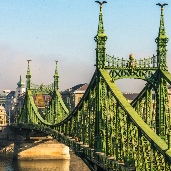 A green metal bridge with ornate towers and repeated structural details
