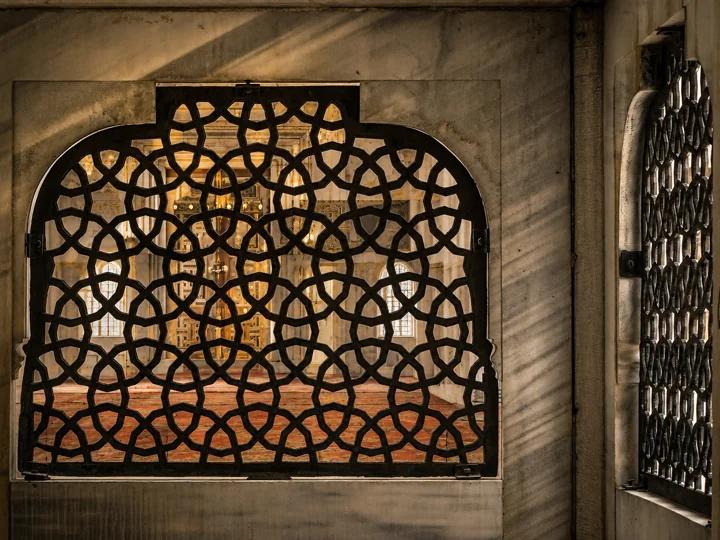 An ornamental metal grille with warm light passing through it