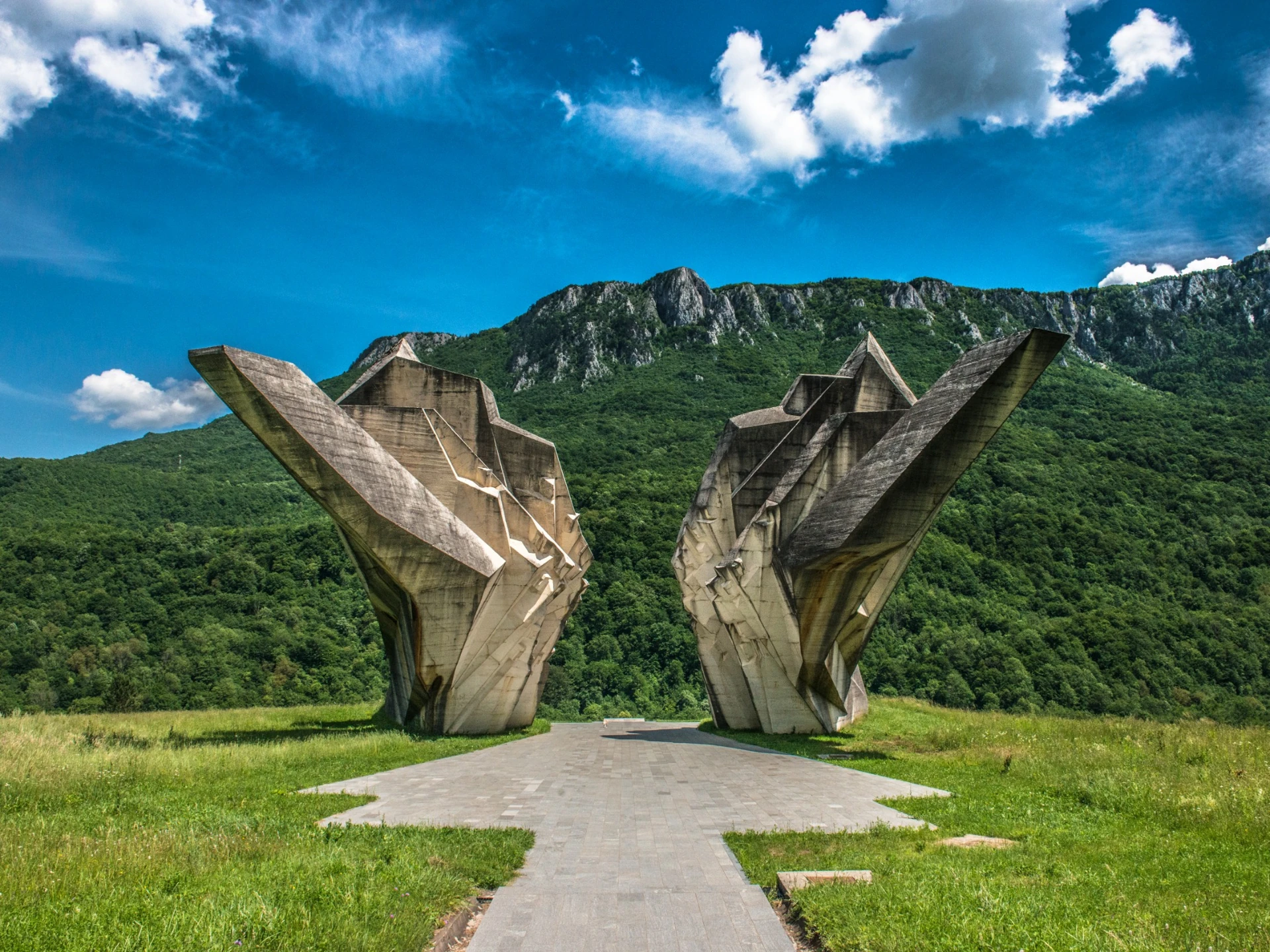 Two angular concrete forms opening towards a mountain ridge